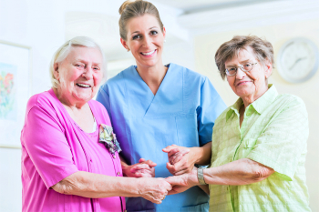 caregiver and two senior women smiling